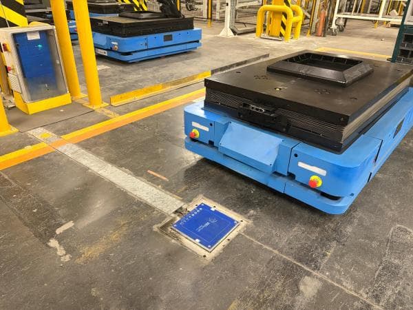 Blue industrial AGV at wireless charging pad